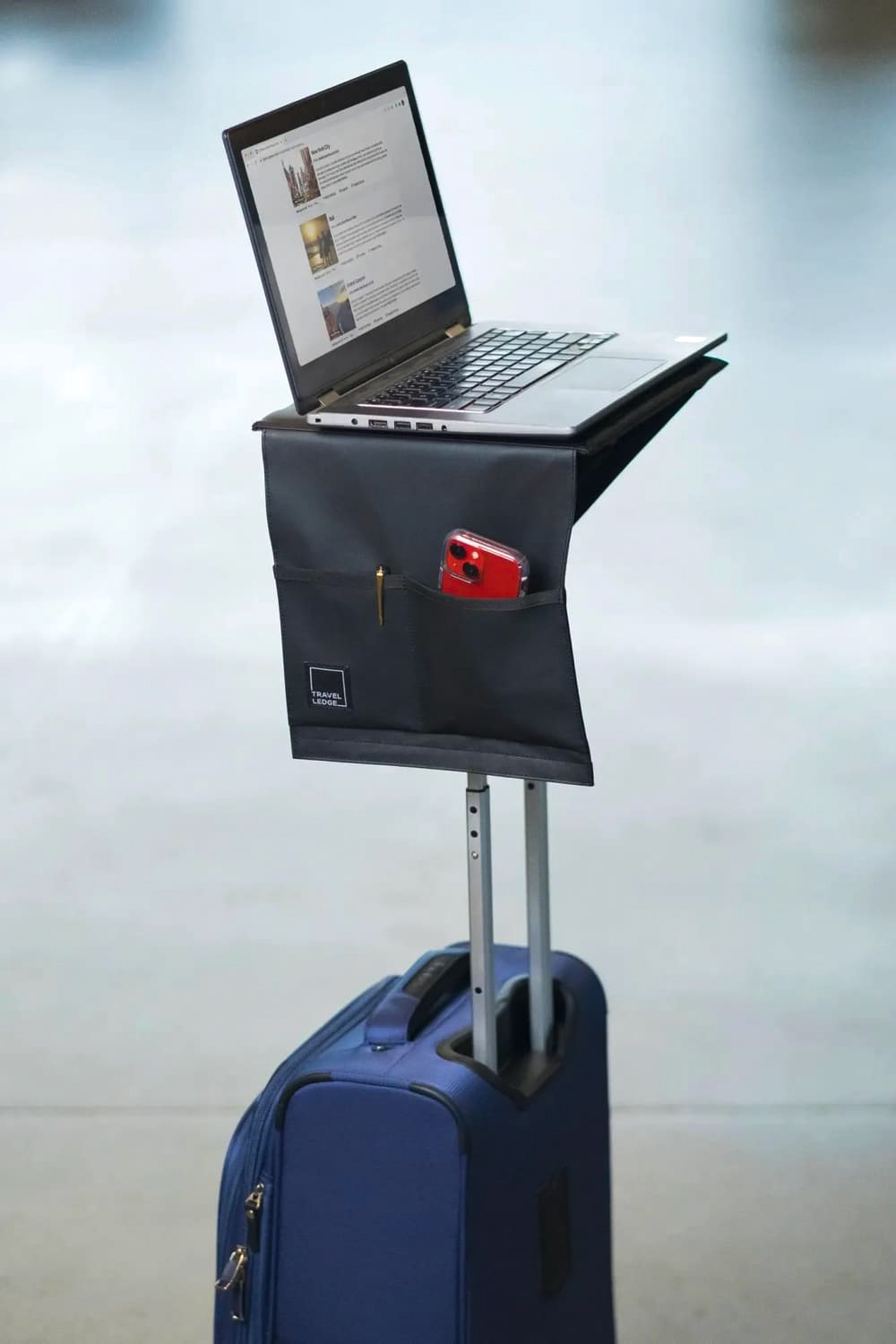 Travel Ledge attached to a blue rolling suitcase with a laptop and travel essentials